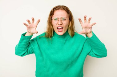 Beyaz arka planda izole edilmiş genç beyaz kadın pençelerini kedi taklidi yaparken gösteriyor, agresif bir hareket..