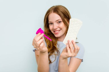 Elinde regl kupası ve mavi arka planda izole edilmiş hijyenik peçete tutan Kafkas genci.