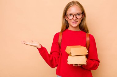 Elinde hamburgerlerle gezen küçük beyaz kız. Bej arka planda bir fotokopi alanı var. Belinde de başka bir el tutuyor..