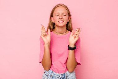 Pembe arka planda izole edilmiş beyaz kız şans getirsin diye dua ediyor.