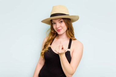 Genç beyaz kadın kumsala yalnız başına gidiyor. Mavi arka planda, seni işaret ediyor. Sanki seni davet ediyormuş gibi..