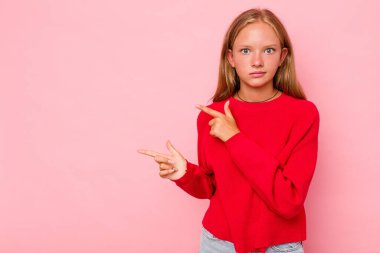 Pembe arka planda izole edilmiş beyaz kız işaret parmağıyla fotokopi alanını işaret ederek şok oldu..