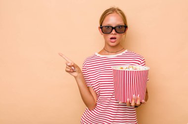 Beyaz kız bej arka planda izole edilmiş patlamış mısır yiyor.