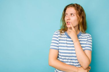 Mavi arka planda soyutlanmış beyaz bir kadın şüpheli ve şüpheci bir ifadeyle yana bakıyor..