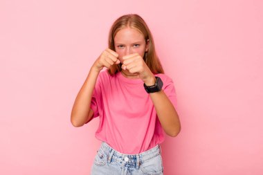 Pembe arka planda izole edilmiş beyaz kız kameraya yumruğunu gösteriyor, agresif yüz ifadesi var..
