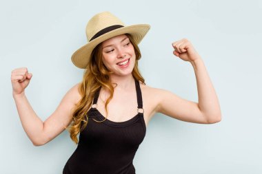 Genç beyaz kadın kumsala yalnız başına gidiyor. Mavi arka planda. Zaferden sonra yumruğunu kaldırıyor..