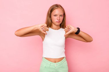 Pembe arka planda izole edilmiş beyaz kız baş parmağını aşağı gösteriyor, hayal kırıklığı konsepti..