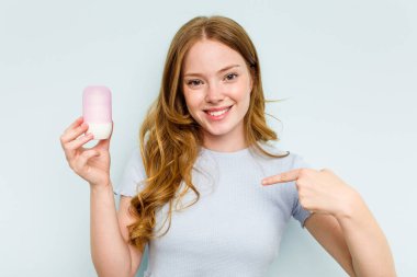 Mavi arka planda deodorant tutan beyaz bir kadın gömleğin fotokopi odasını işaret ediyor, gururlu ve kendinden emin.