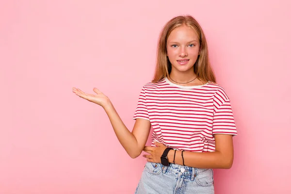 stock image Caucasian teen girl isolated on pink background showing a copy space on a palm and holding another hand on waist.