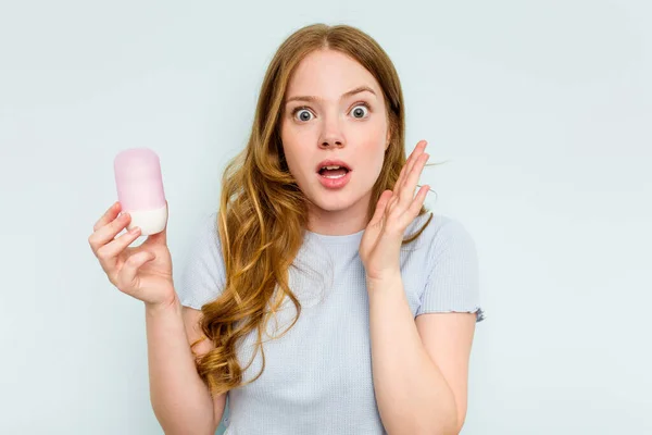 Ung Kaukasisk Kvinna Håller Deodorant Isolerad Blå Bakgrund Förvånad Och — Stockfoto