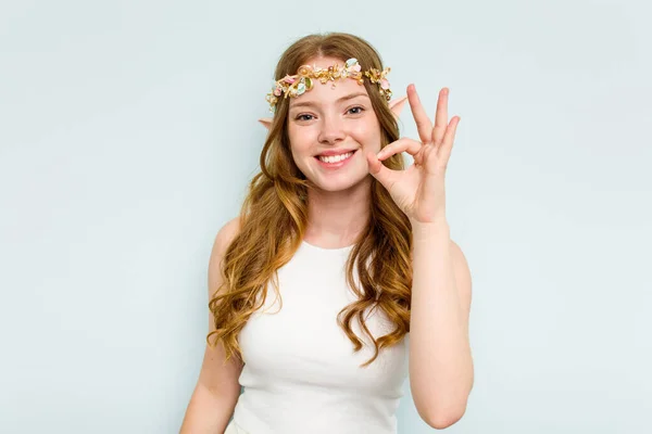 Young elf woman isolated on blue background cheerful and confident showing ok gesture.