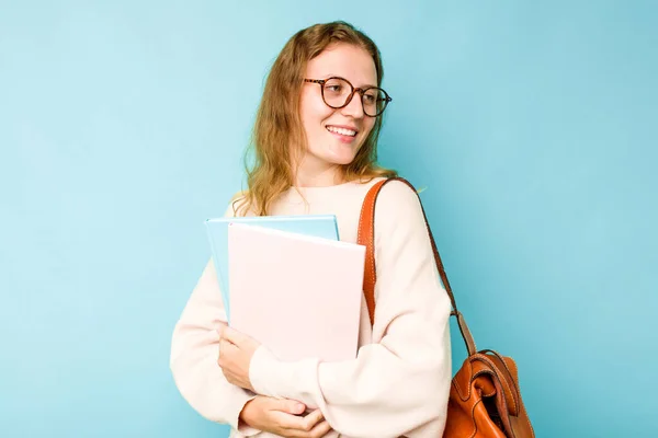 Jonge Student Kaukasische Vrouw Geïsoleerd Blauwe Achtergrond Kijkt Opzij Glimlachend — Stockfoto