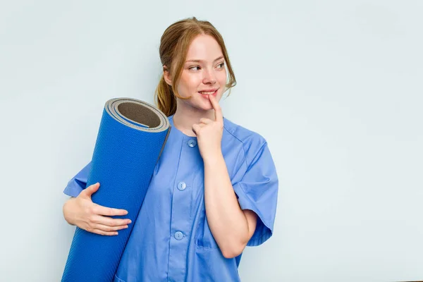 Junge Kaukasische Physiotherapeutin Hält Eine Matte Isoliert Auf Blauem Hintergrund — Stockfoto