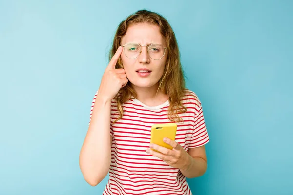 Mladá Běloška Drží Mobilní Telefon Izolovaný Modrém Pozadí Ukazuje Zklamání — Stock fotografie