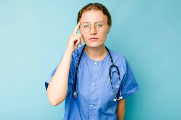 Jovem Enfermeira Mulher Caucasiana Isolado Fundo Azul Apontando Templo Com — Fotografia de Stock