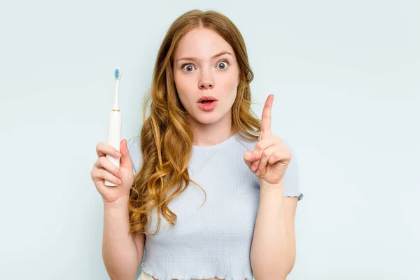 青い背景に孤立した電動歯ブラシを持つ若い白人女性は いくつかの素晴らしいアイデア 創造性の概念を持っている — ストック写真