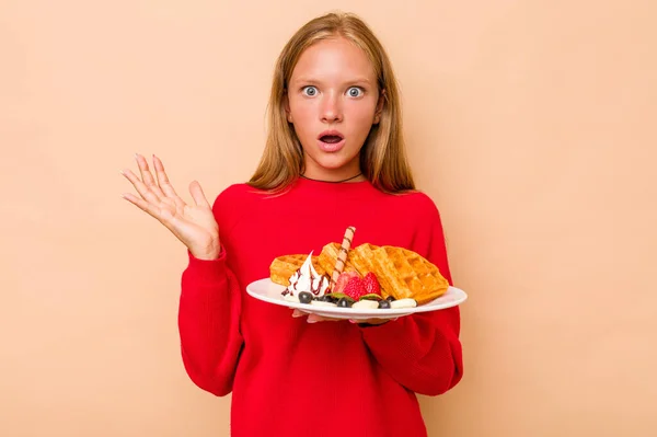 Menina Caucasiana Segurando Waffles Isolado Fundo Bege Surpreso Chocado — Fotografia de Stock