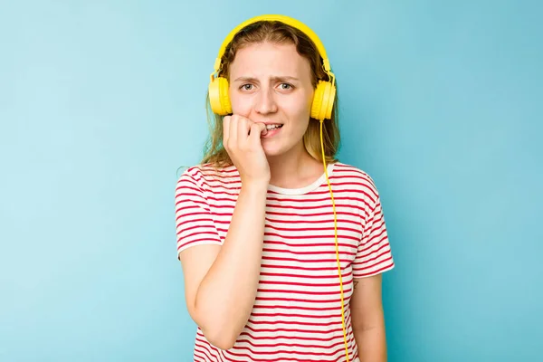 Młoda Biała Kobieta Nosi Słuchawki Izolowane Niebieskim Tle Obgryzając Paznokcie — Zdjęcie stockowe