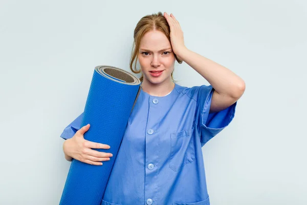 Young Caucasian Physiotherapist Holding Mat Isolated Blue Background Being Shocked — Stock Photo, Image