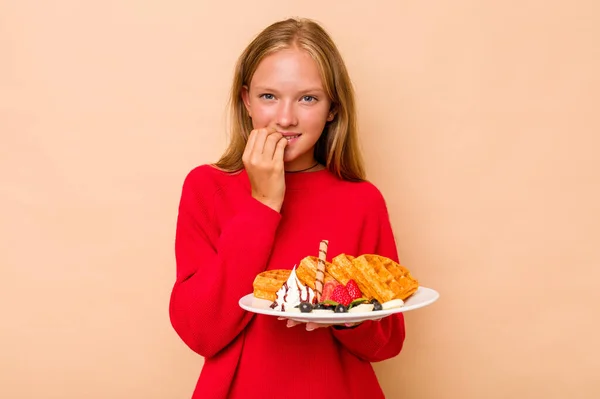 Menina Caucasiana Segurando Waffles Isolado Fundo Bege Mordendo Unhas Nervoso — Fotografia de Stock