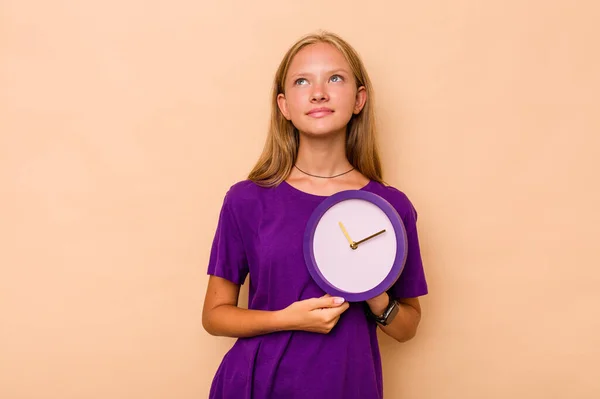 Μικρή Καυκάσια Κοπέλα Κρατώντας Ένα Ρολόι Απομονωμένο Μπεζ Φόντο Ονειρεύεται — Φωτογραφία Αρχείου