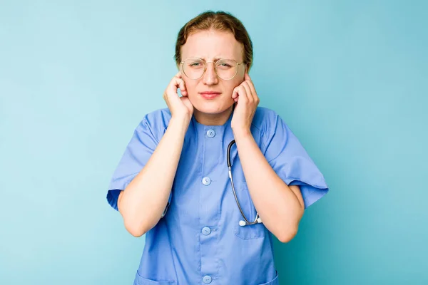 Jovem Enfermeira Caucasiana Isolada Fundo Azul Cobrindo Orelhas Com Mãos — Fotografia de Stock