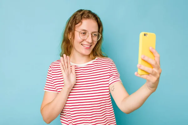 年轻的高加索女人拿着蓝色背景的手机 — 图库照片