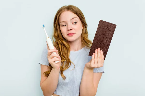Junge Kaukasische Frau Hält Schokolade Und Zahnbürste Isoliert Auf Blauem — Stockfoto