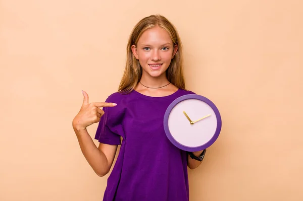 Маленька Біла Дівчинка Тримає Годинник Ізольовано Бежевому Фоні Вказуючи Вручну — стокове фото
