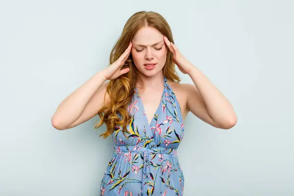 stock image Young caucasian woman isolated on blue background having a head ache, touching front of the face.