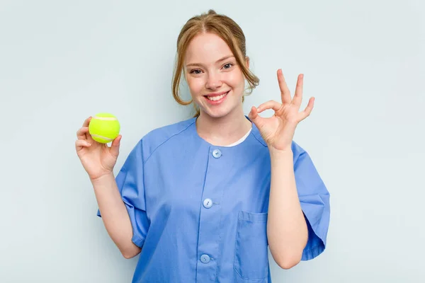 Young Caucasian Physiotherapist Holding Tennis Ball Isolated Blue Background Cheerful — Stock Photo, Image