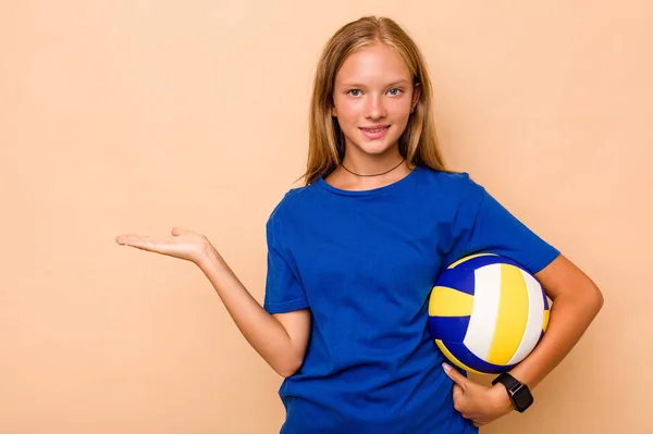 一个高加索小女孩打的排球 背景是米黄色的 手掌上有一个复制的空间 腰部有另一只手 — 图库照片
