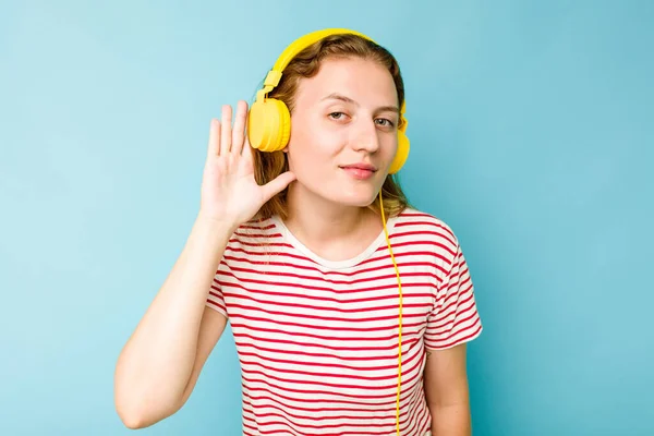 Jovem Caucasiana Usando Fones Ouvido Isolados Fundo Azul Tentando Ouvir — Fotografia de Stock