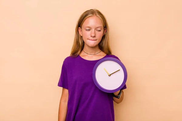 Niña Caucásica Sosteniendo Reloj Aislado Sobre Fondo Beige Confundido Siente —  Fotos de Stock