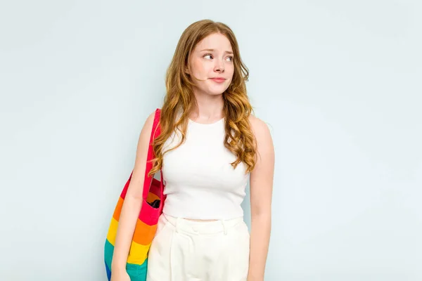 stock image Young caucasian woman holding LGTBI bag isolated on blue background confused, feels doubtful and unsure.