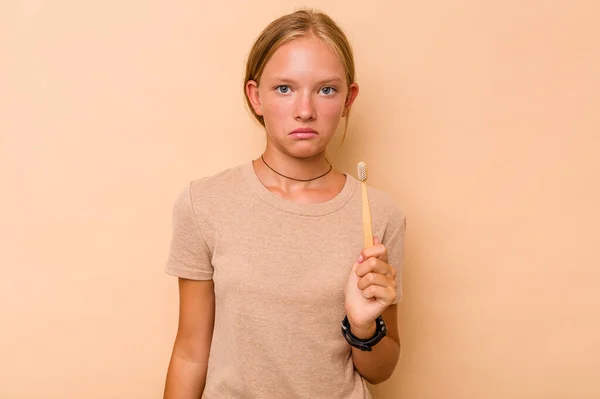 Caucasian Teen Girl Brushing Teeth Isolated Beige Background Shrugs Shoulders — Stock Photo, Image