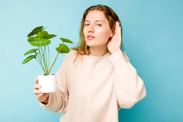 Молодая Белая Женщина Держащая Растение Голубом Фоне Пытается Слушать Сплетни — стоковое фото