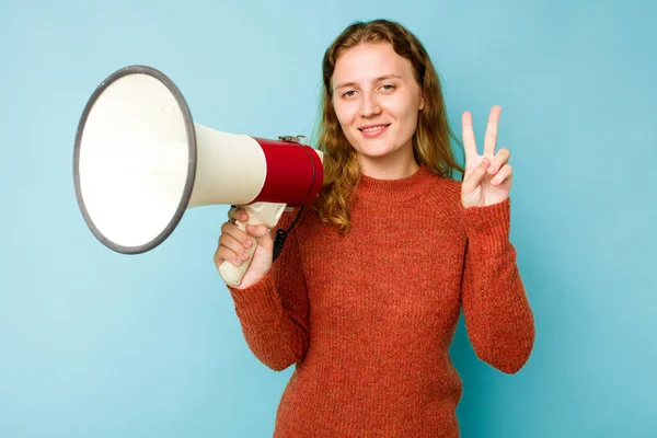 stock image Young caucasian woman holding megaphone isolated on blue background showing number two with fingers.