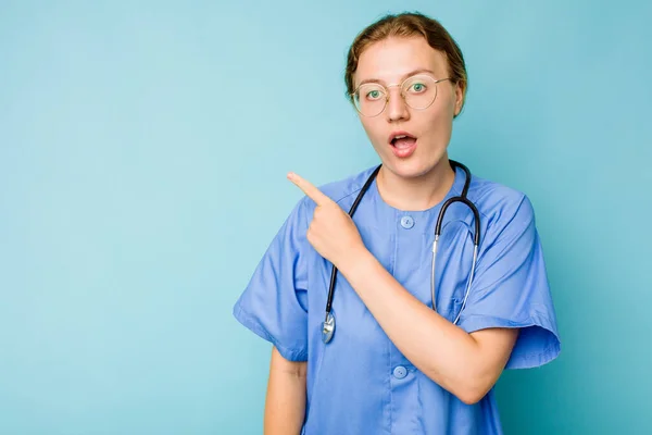Jovem Enfermeira Mulher Caucasiana Isolado Fundo Azul Apontando Para Lado — Fotografia de Stock