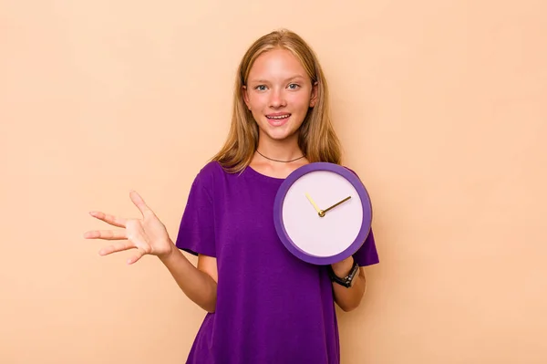 Μικρή Καυκάσιος Κορίτσι Κρατώντας Ένα Ρολόι Απομονώνονται Μπεζ Φόντο Λαμβάνουν — Φωτογραφία Αρχείου