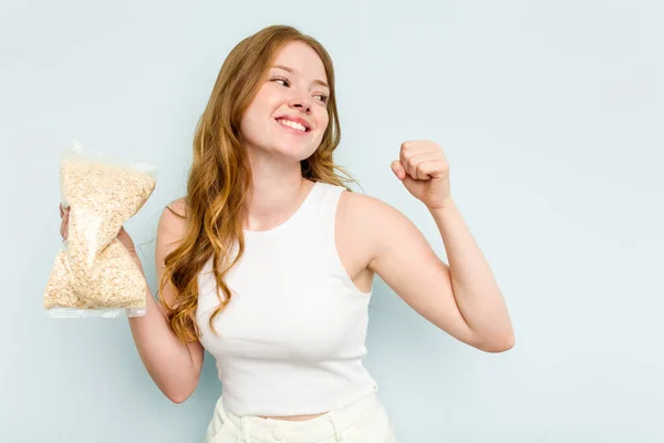 Young Caucasian Woman Holding Oatmeal Isolated Blue Background Raising Fist — Stock Photo, Image