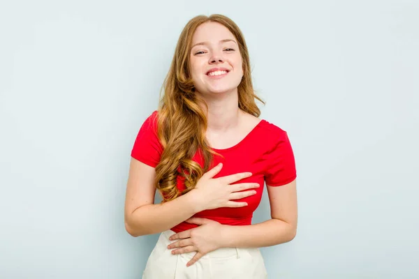 stock image Young caucasian woman isolated on blue background laughs happily and has fun keeping hands on stomach.