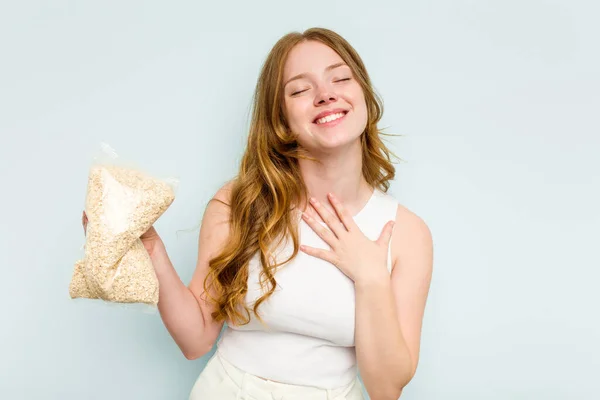 Young Caucasian Woman Holding Oatmeal Isolated Blue Background Laughs Out — Stock Photo, Image