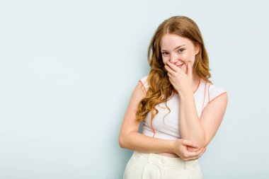 Mavi arka planda soyutlanmış genç beyaz kadın gülüyor, kaygısız, doğal duygu..