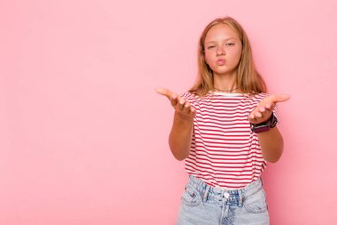 Pembe arka planda izole edilmiş beyaz bir kız dudaklarını kıvırıyor ve hava öpücüğü yollamak için avuç içi tutuyor..
