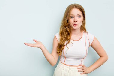 Mavi arka planda izole edilmiş genç beyaz kadın bir avuç içinde fotokopi alanı ve belinde bir el daha gösteriyor..