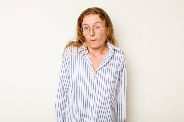 Beyaz arka planda izole edilmiş genç beyaz kadın omuzlarını silker ve gözleri açık kalır..