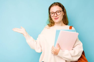 Mavi arka planda izole edilmiş genç beyaz kadın bir avuç içinde fotokopi alanı ve belinde bir el daha gösteriyor..