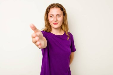 Beyaz arka planda izole edilmiş genç beyaz kadın selamlaşma jesti olarak kameraya elini uzatıyor..