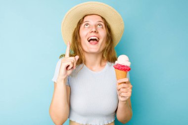 Elinde dondurma tutan beyaz bir kadın, ağzı açık mavi bir arkaplan buldu..